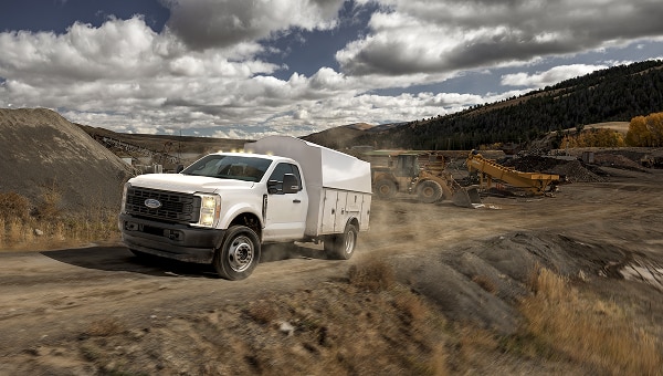 Ford Super Duty Chasis blanca con carrocería de servicio transitando por un sitio de construcción o cantera.